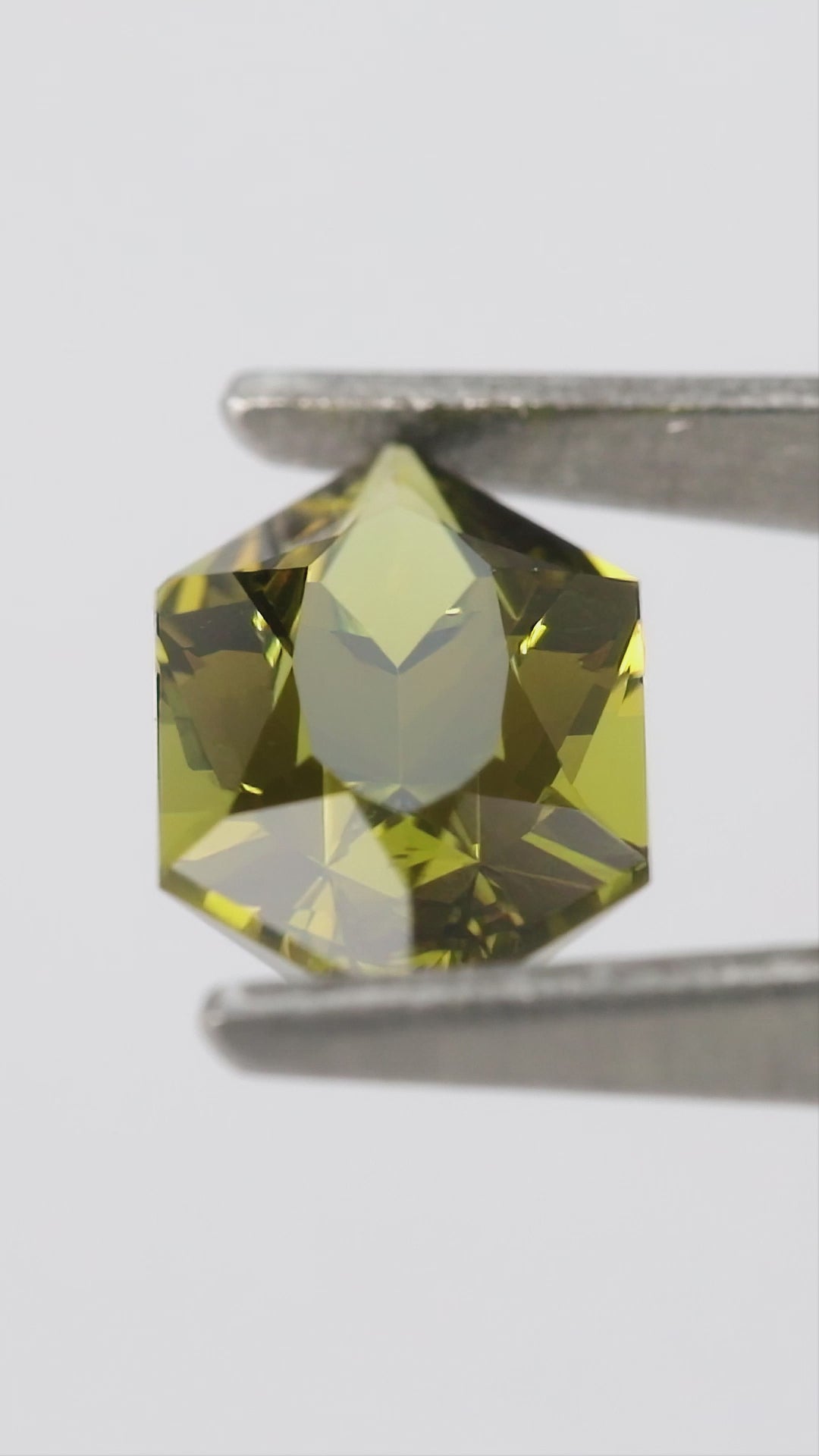 Natural-light views of the representative BLS201 olive-green lab-grown sapphire, including face-up, reverse and finger scale.