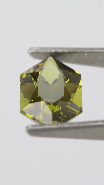 Natural-light views of the representative BLS201 olive-green lab-grown sapphire, including face-up, reverse and finger scale.