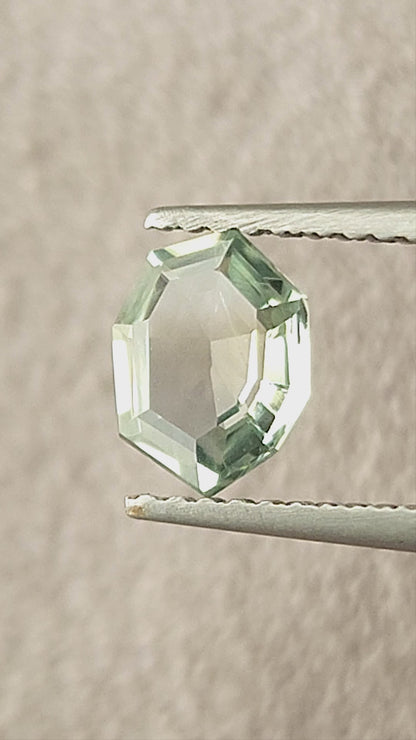 Mint green octagonal sapphire shown rotating in tweezers, between fingertips and on a white pad.