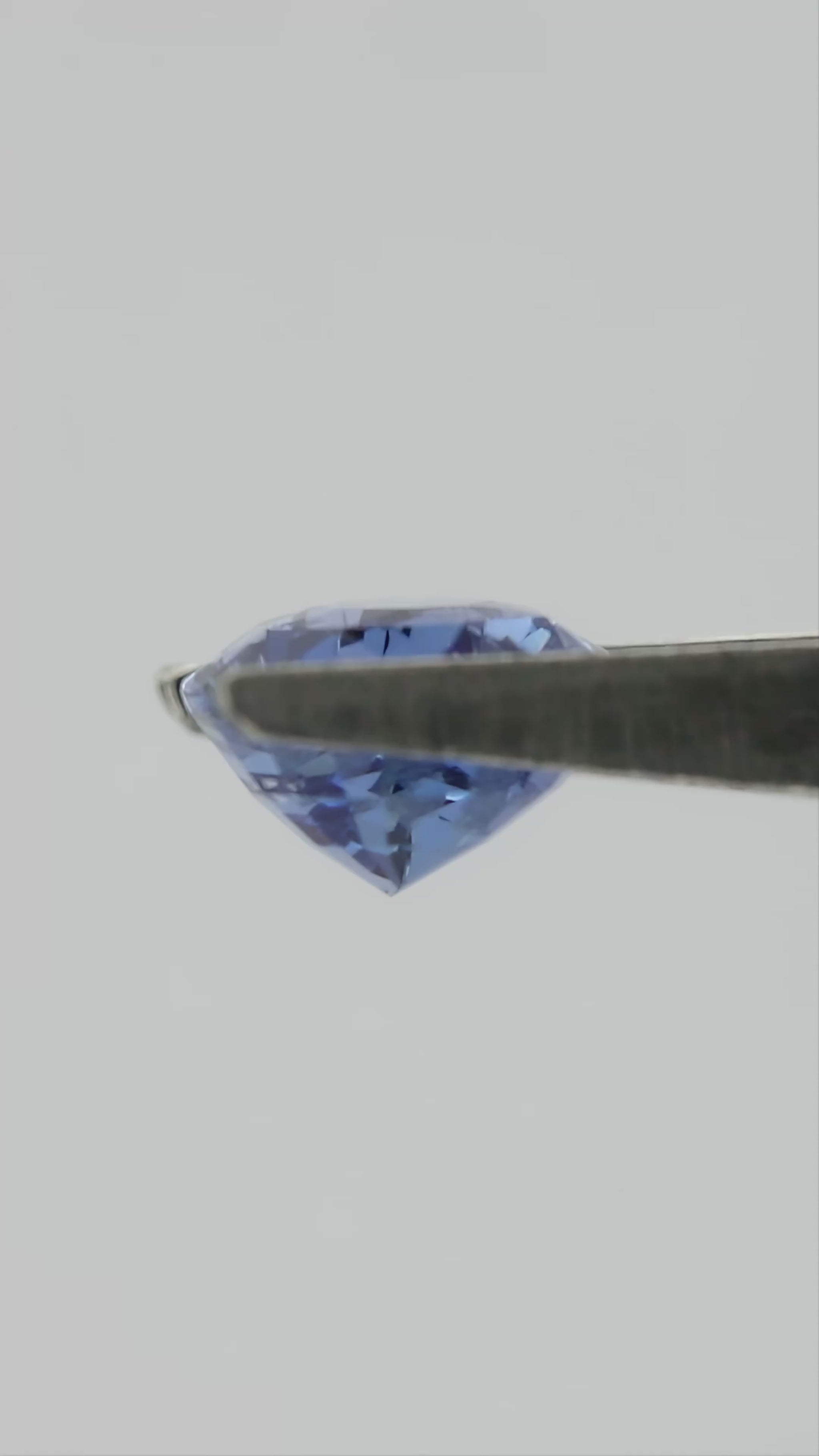 Video of the exact pear-shaped light blue sapphire rotating in tweezers, followed by a between-fingers scale view.