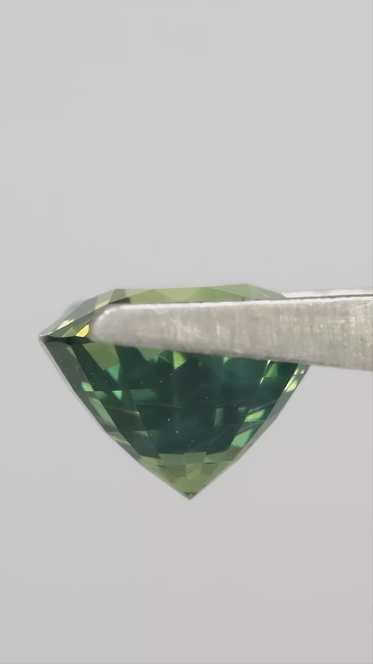 Video showing the olive teal green round sapphire through changing viewing angles.