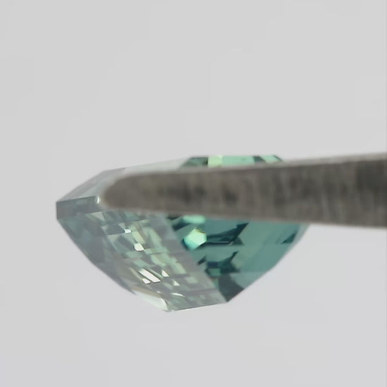 Video showing the light teal green emerald-cut sapphire through changing viewing angles.