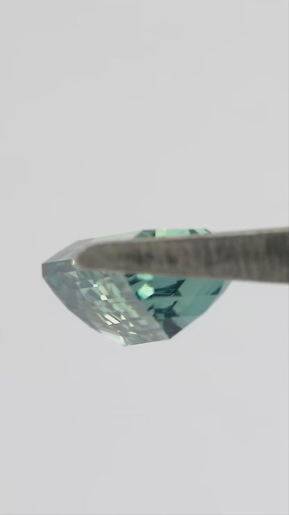Video showing the light teal green emerald-cut sapphire through changing viewing angles.