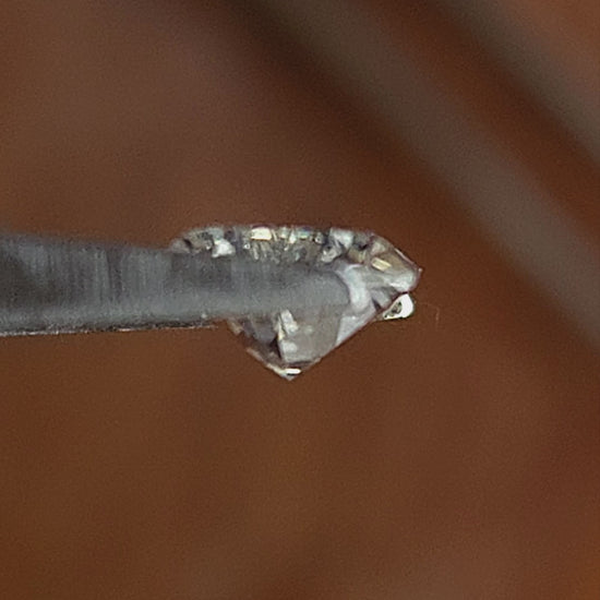Elongated hexagon Dutch marquise diamond rotated in tweezers and shown on fingers for scale.