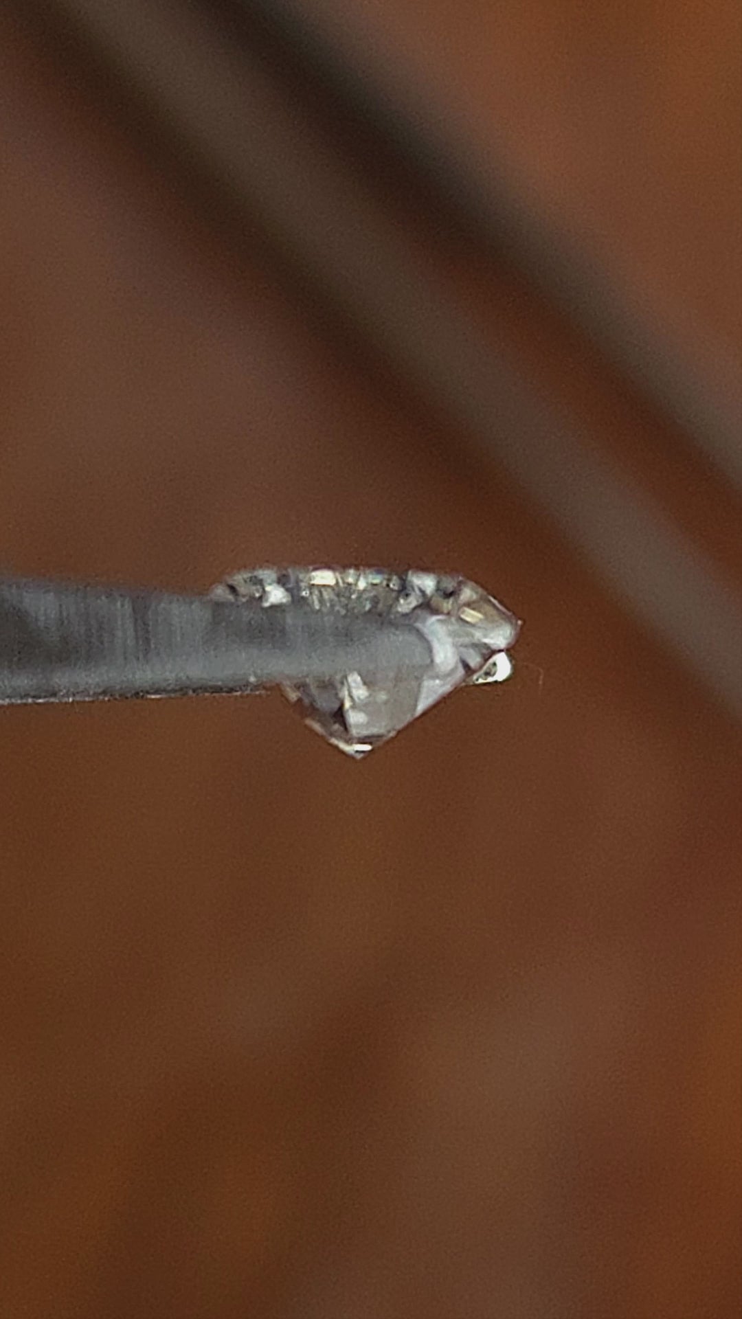 Elongated hexagon Dutch marquise diamond rotated in tweezers and shown on fingers for scale.