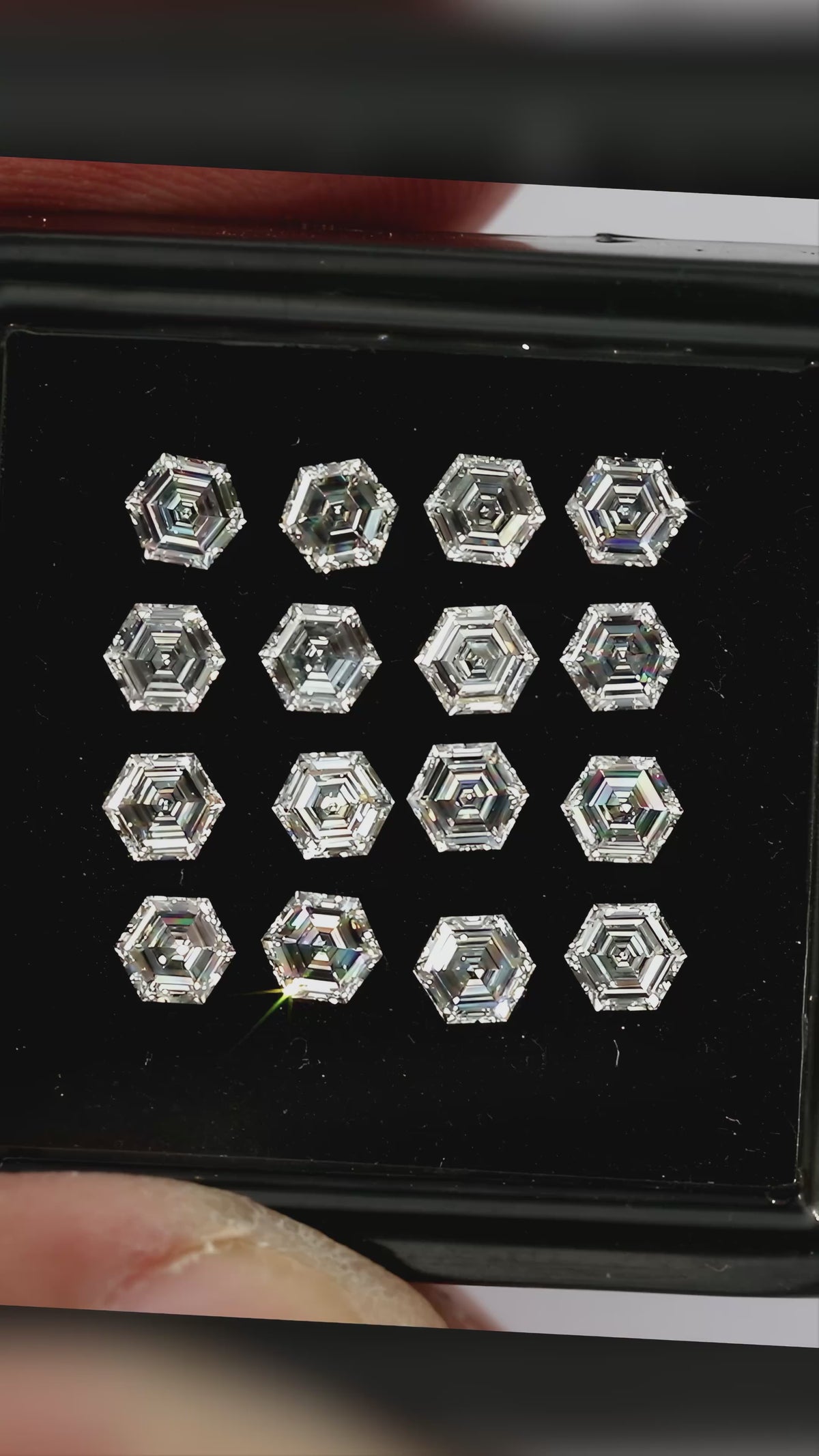 Video showing hexagonal diamonds in a black tray and in a palm, plus an isolated single-diamond close-up, with different step-facet reflections.