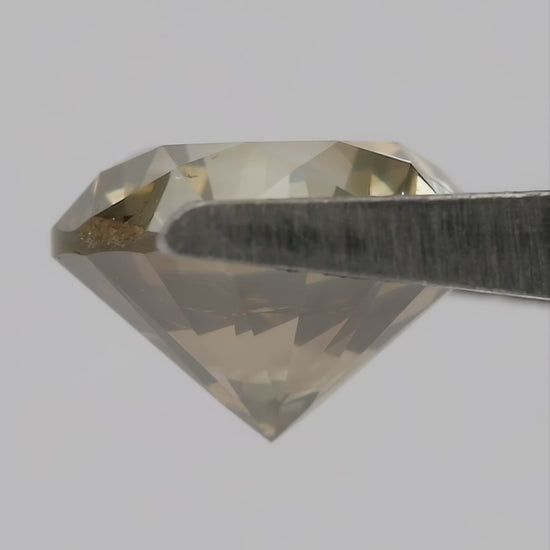 4K video of the exact KL445 round brilliant diamond rotating through face-up, angled, profile and hand-scale views, showing olive champagne color and prominent visible features.