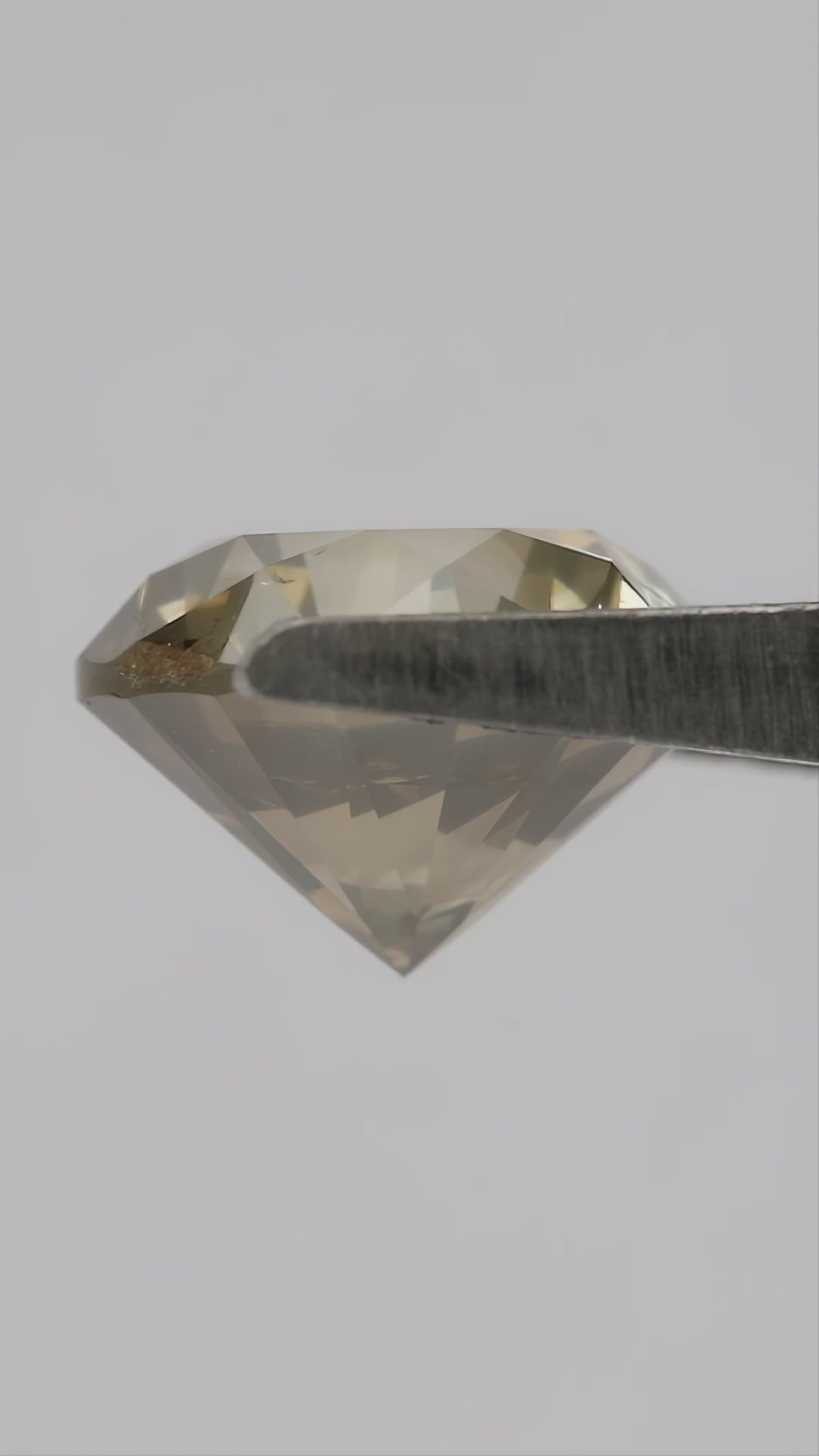 4K video of the exact KL445 round brilliant diamond rotating through face-up, angled, profile and hand-scale views, showing olive champagne color and prominent visible features.