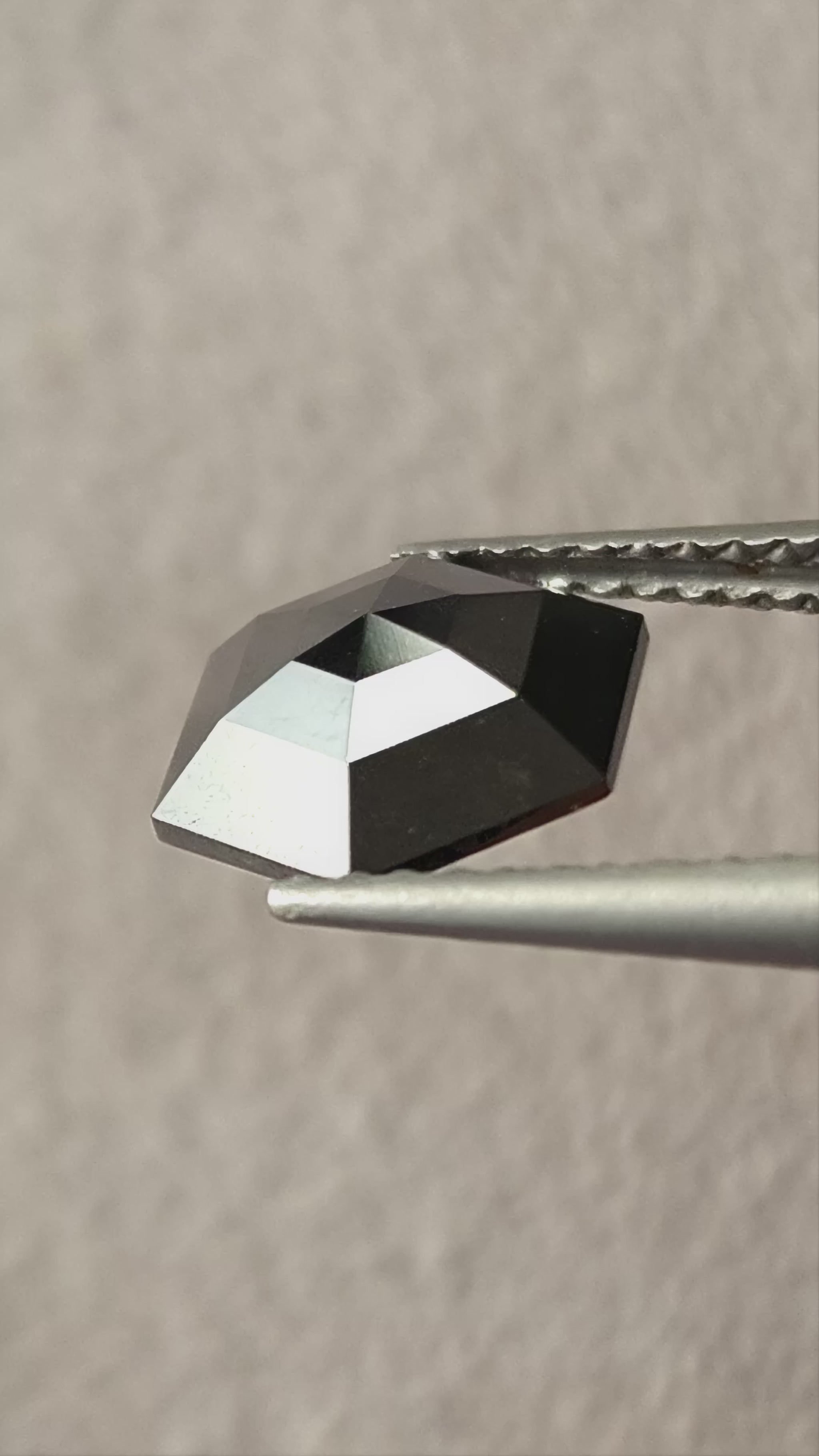 Video of the exact 1.64 ct natural black rose-cut geometric hexagon diamond, showing silver-and-black reflections as it moves.