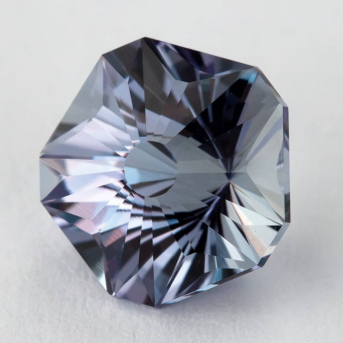 Tilted Hanami-cut sapphire showing its five-sided outline and a shifted pattern of blue-gray reflections.