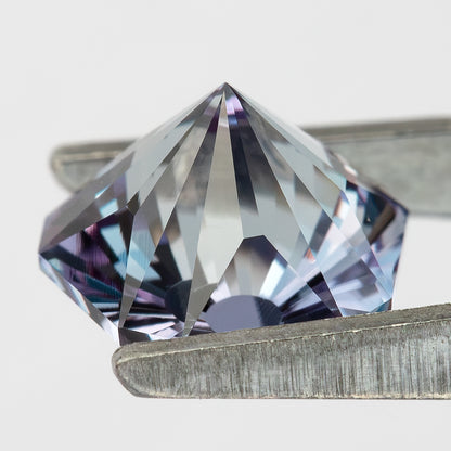 Oblique pavilion profile of the pentagon sapphire in tweezers, showing its pointed underside and depth.