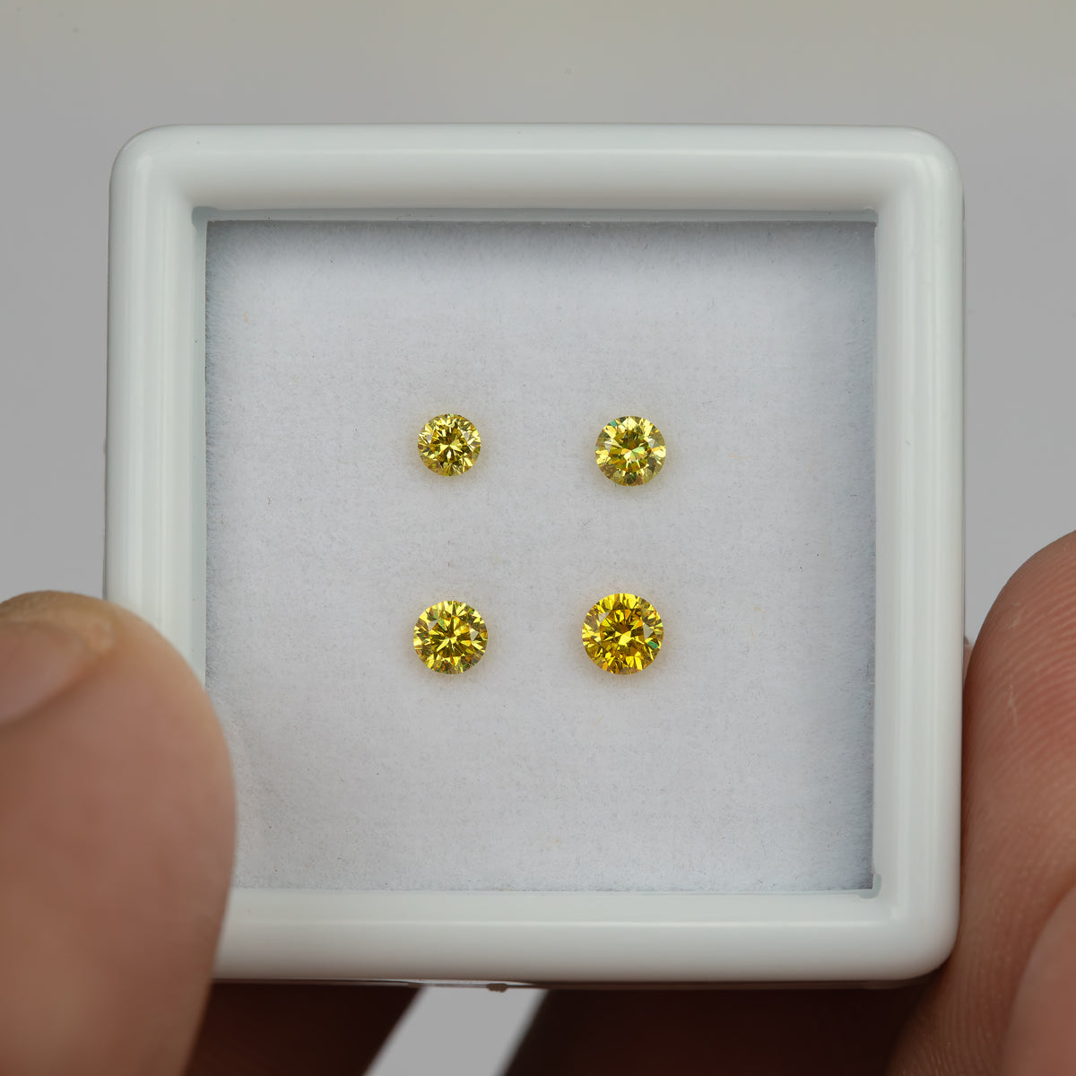 White tray of four yellow diamonds held between fingers in an alternate front view.