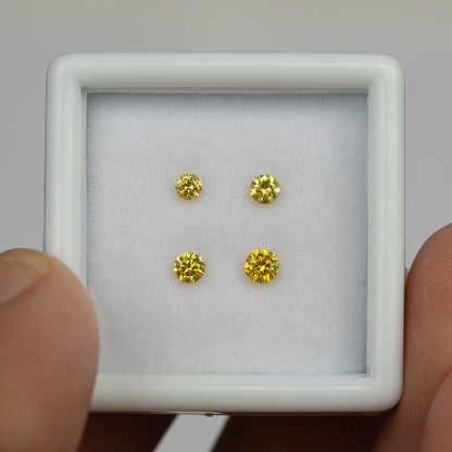 White tray of four yellow diamonds held between fingers in an alternate front view.
